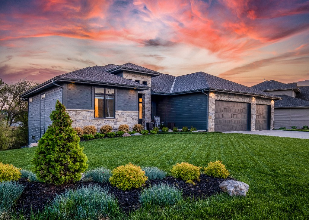 A modern Houston home at dusk with a manicured lawn beneath a sunset sky