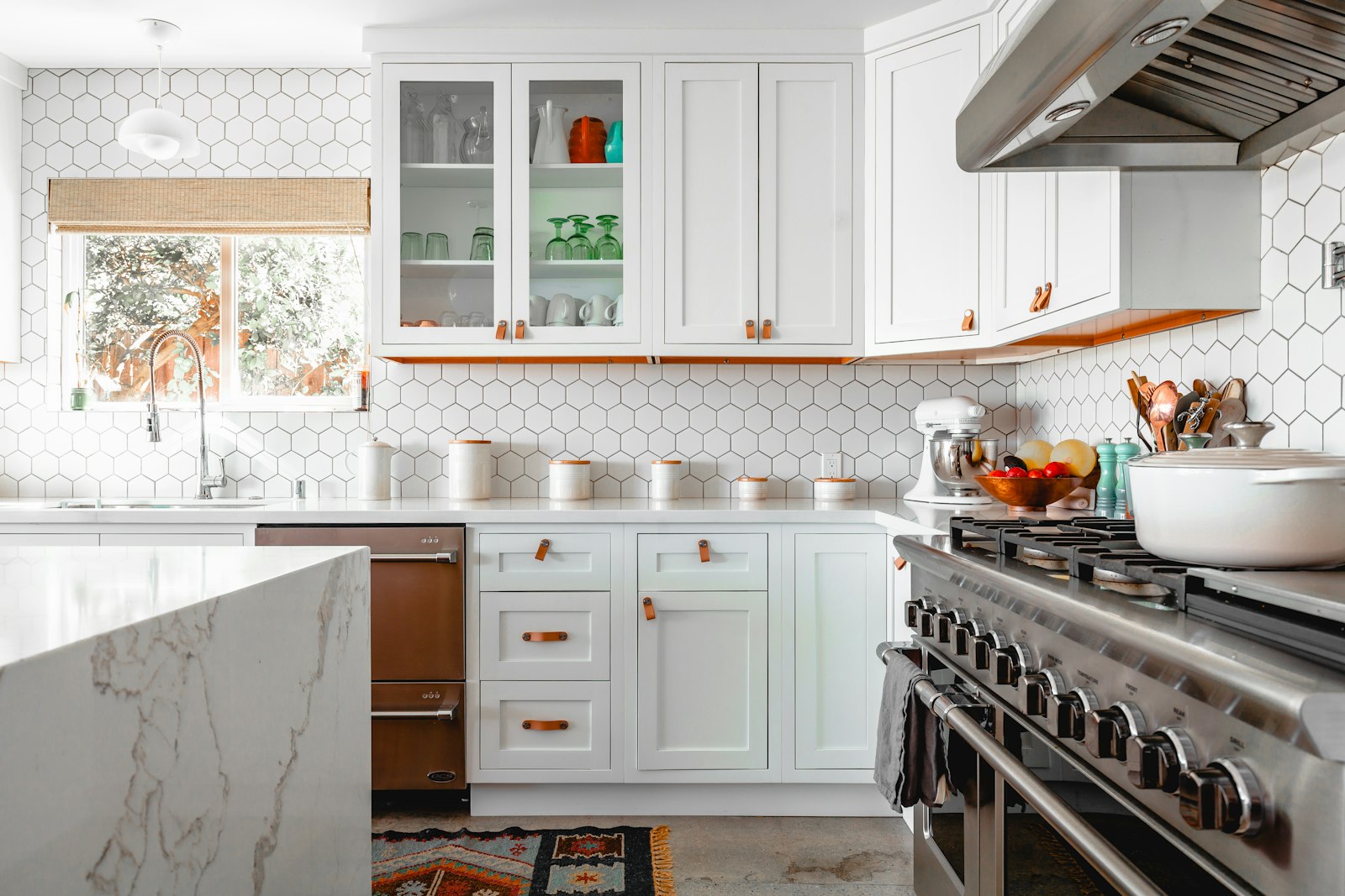 A bright kitchen with white cabinetry and a marble island